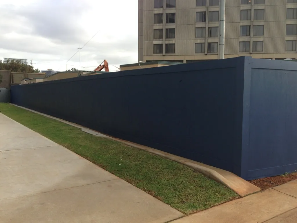 Tall blue fence near hotel building.